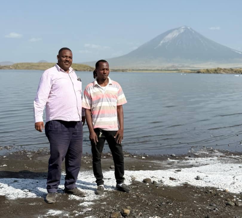 Community representatives standing by the lake with Mount Meru in the background