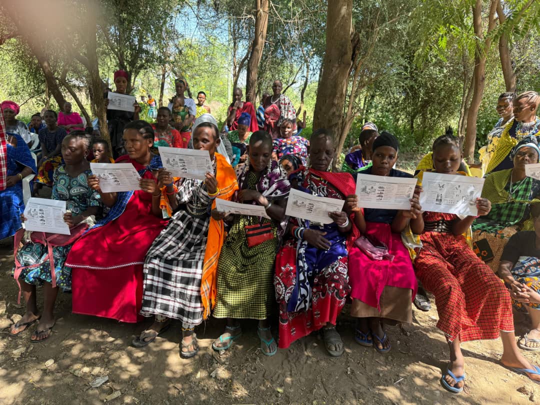 Maasai women holding educational materials during outdoor awareness session
