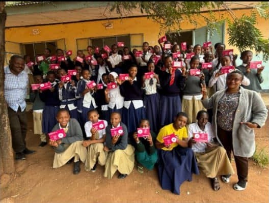 Schoolgirls proudly holding reusable sanitary kits